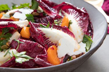 Close-up of a large ceramic salad bowl filled with dressed Trevisano radicchio, mandarin orange segments, herbs, pistachios, and ricotta salata.