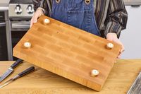Person holding a Boardsmith Maple End-Grain Cutting Board with feet attached