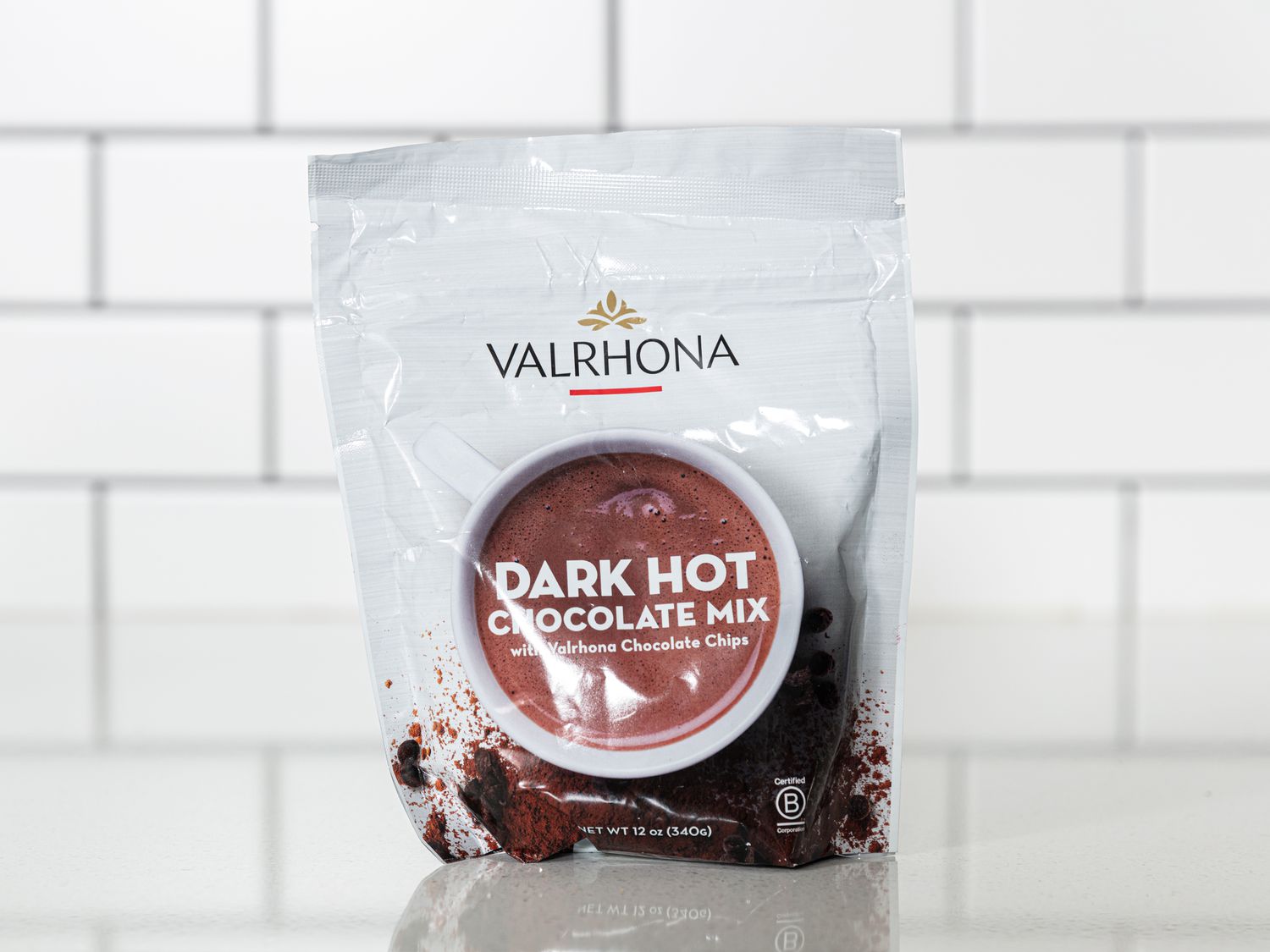 Bag of Valrhona Dark Hot Chocolate mix on white surface with white tile background