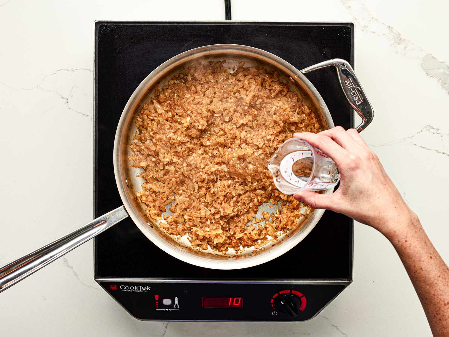 Overhead view of adding water to browned onions