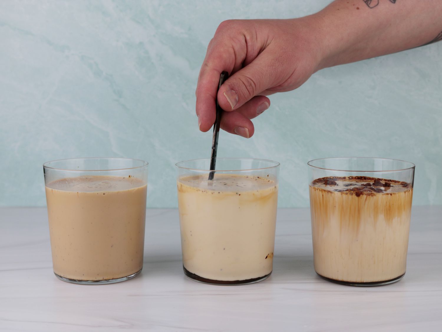 a hand stirring instant espresso into cold milk to make an iced latte