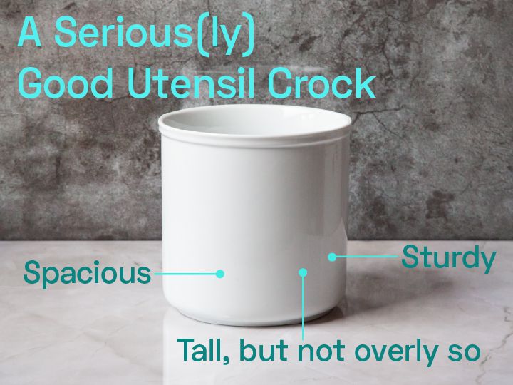 A white utensil crock on a marble countertop.