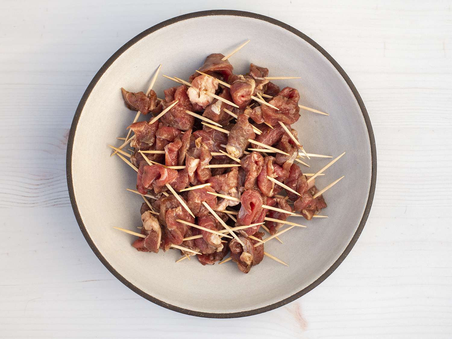 Pile of marinated lamb pieces threaded on toothpicks on a plate