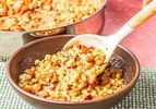 Bowl of barley and cranberry bean soup being served with a spoon dish in a rustic setting
