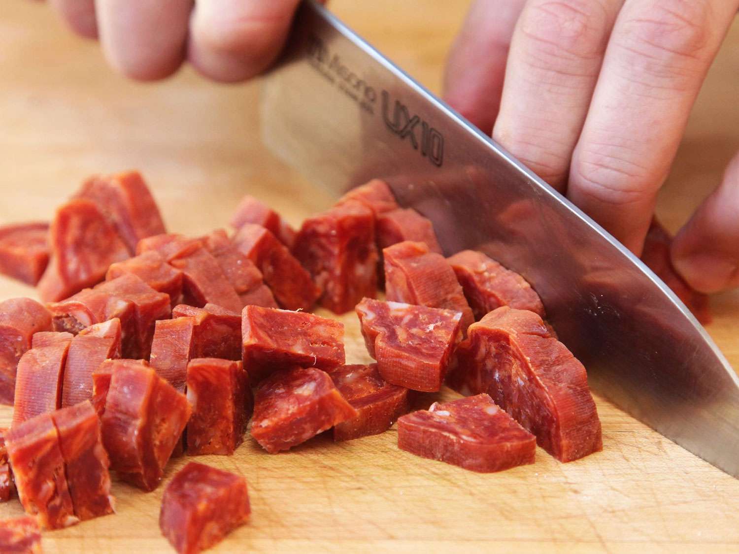 Closeup of chorizo being cut into thick, quartered slices.