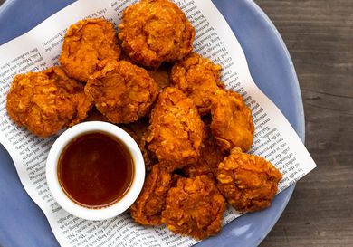 A pile of homemade chicken nuggets with a bowl of sweet 'n' sour sauce