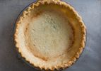 A blind-baked golden brown pie crust inside of a glass pie plate.