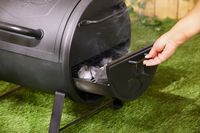 A person pulling out the firebox on the Char-Griller grill.