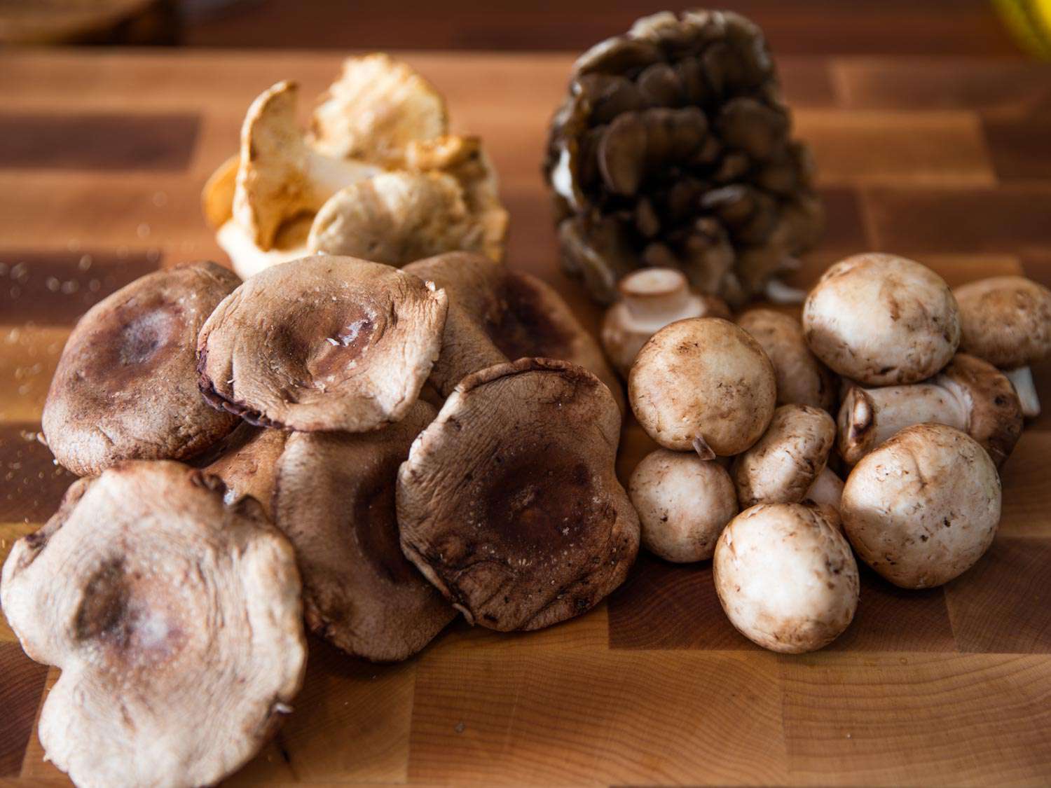 An assortment of mushrooms piled on a cutting board.