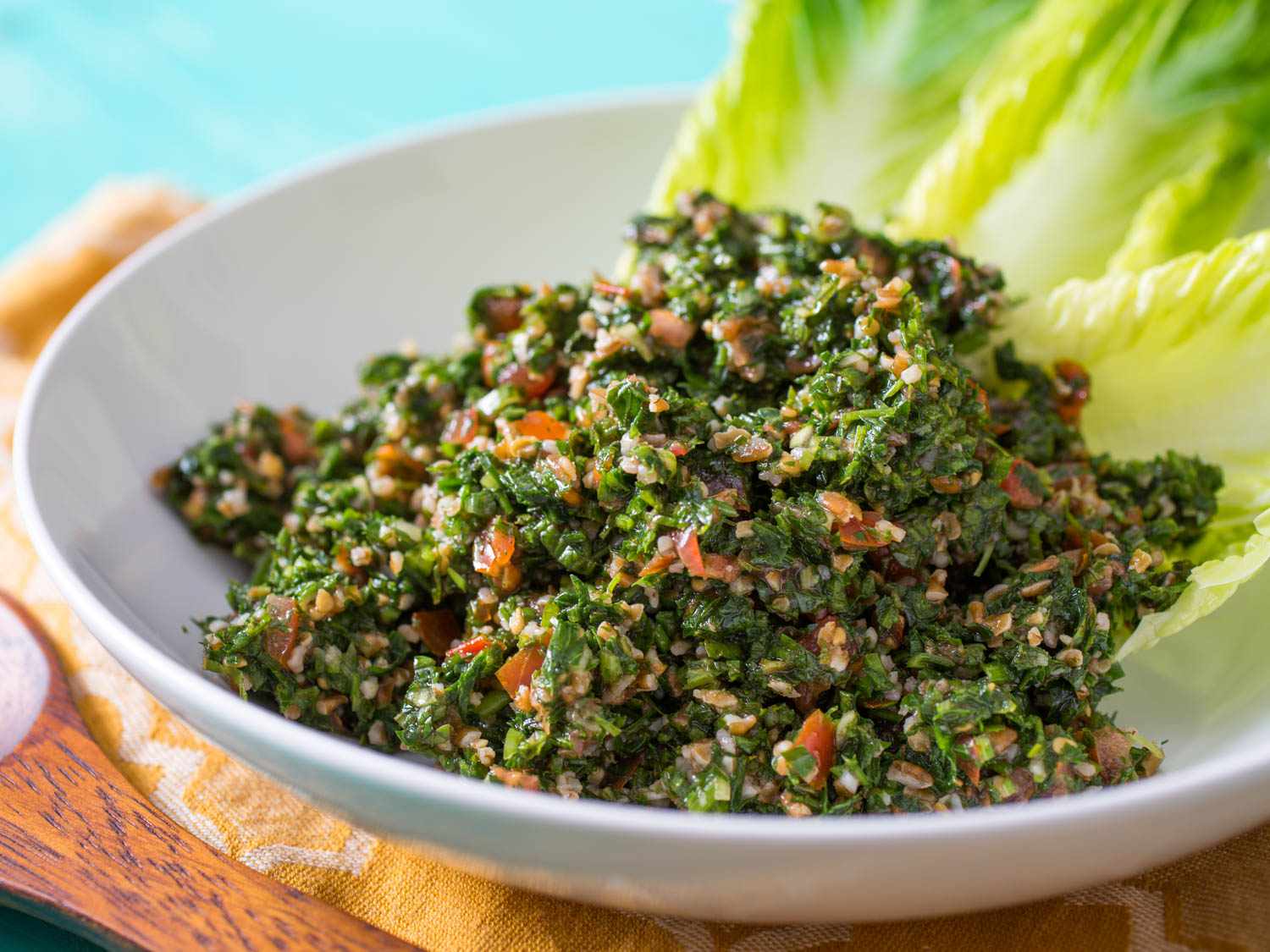 A bowl filled with tabbouleh atop romaine lettuce hearts. 