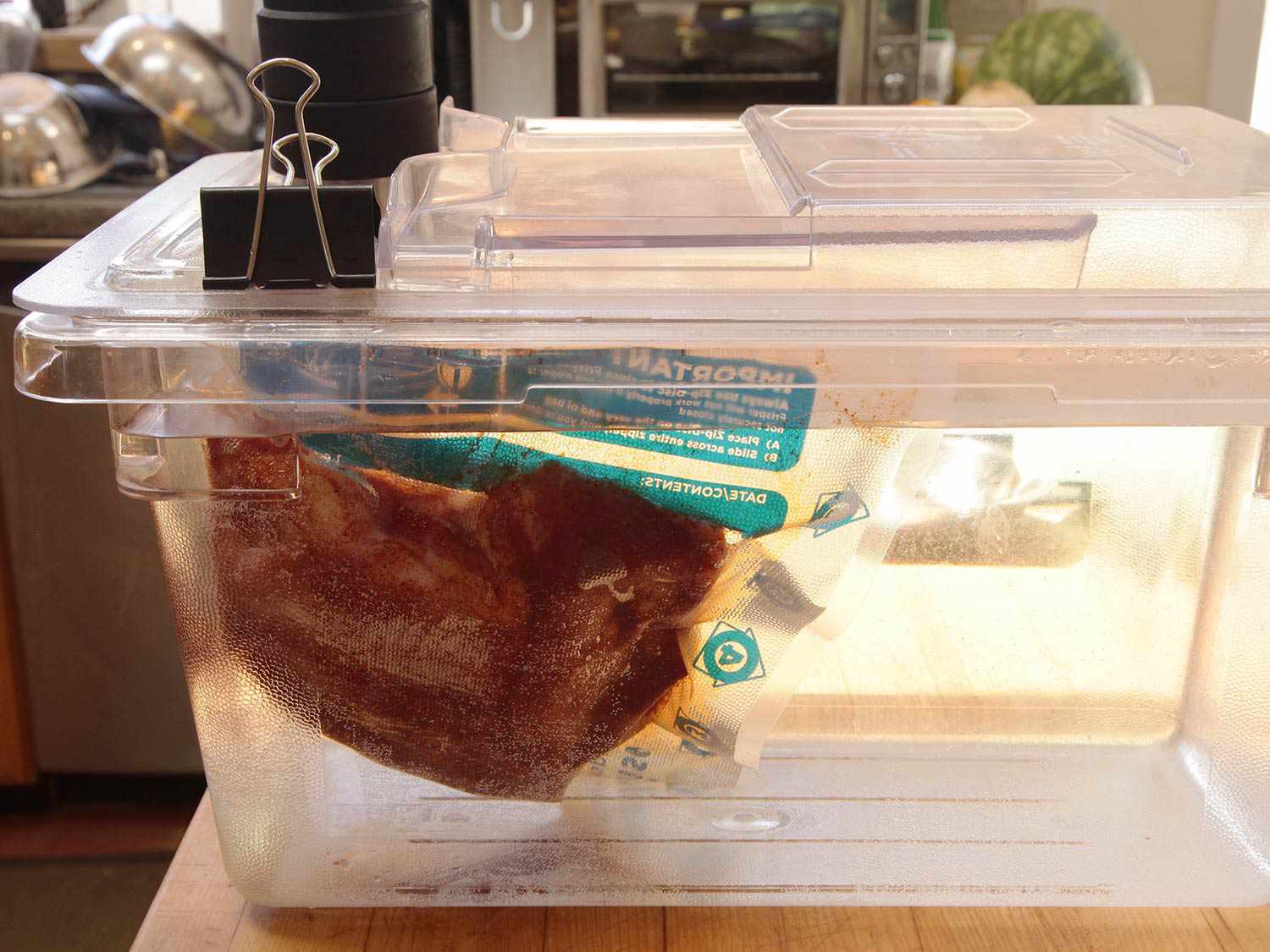 Pork shoulder in a clear lidded plastic container with water and a sous vide circulator