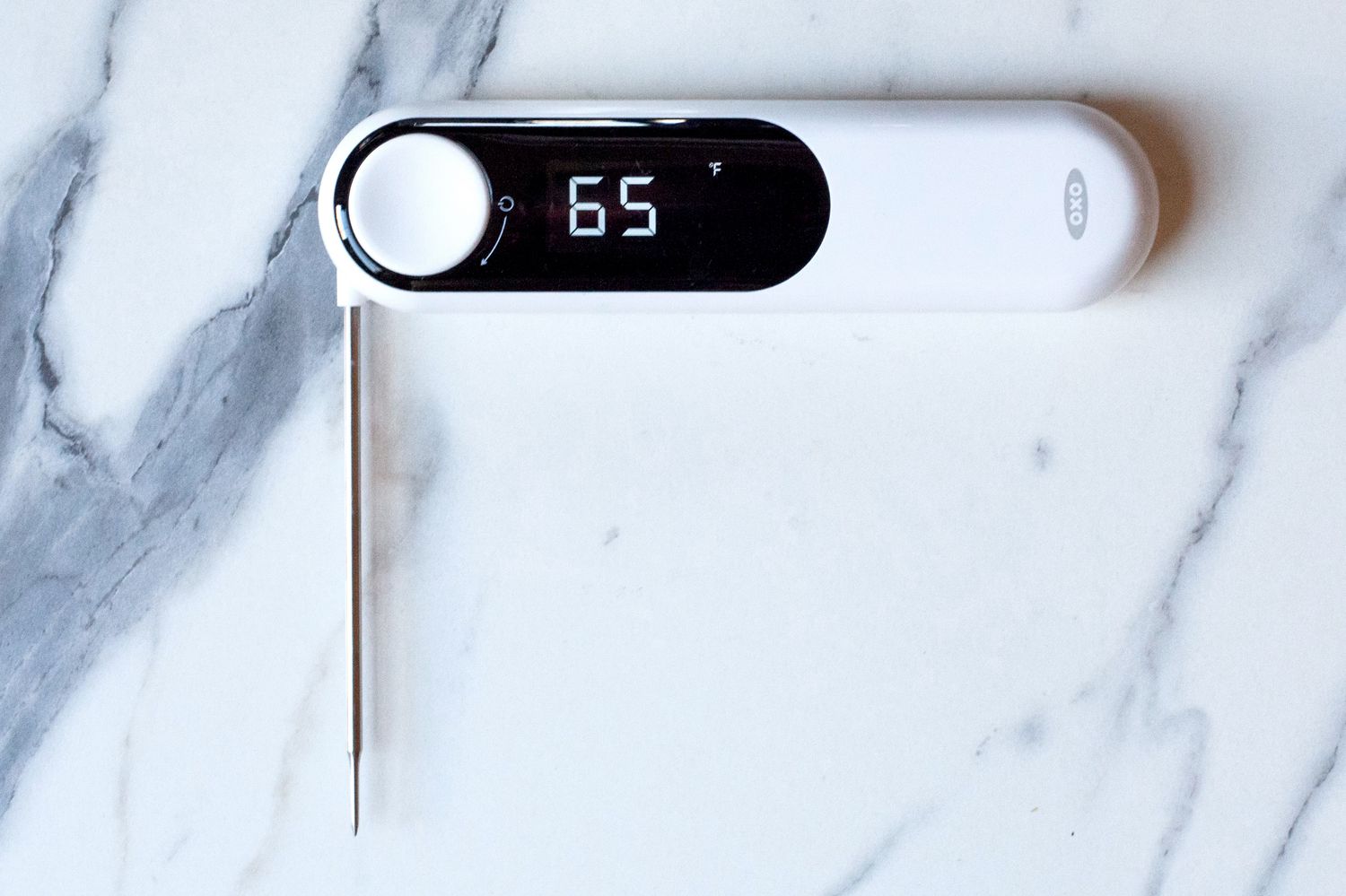 The OXO thermometer with its probe out on a marble countertop.