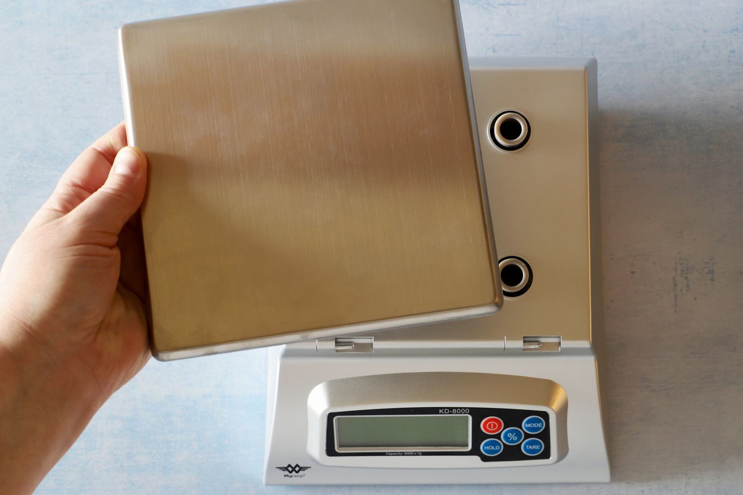 A person removing the platform of the My Weigh kitchen scale.