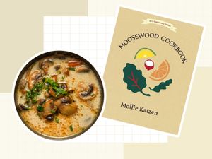 A bowl of soup and the cover of the Moosewood Cookbook featuring a title and illustrations of food elements