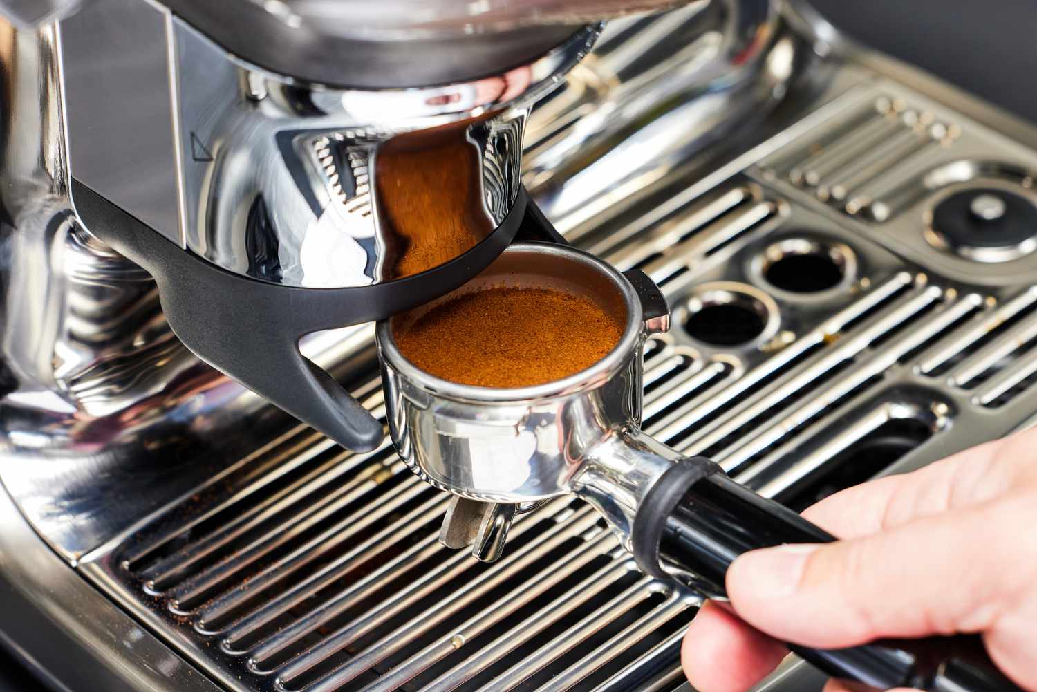 A person adjusting the portafilter onto the Breville Barista Touch Impress Espresso Machine with Grinder
