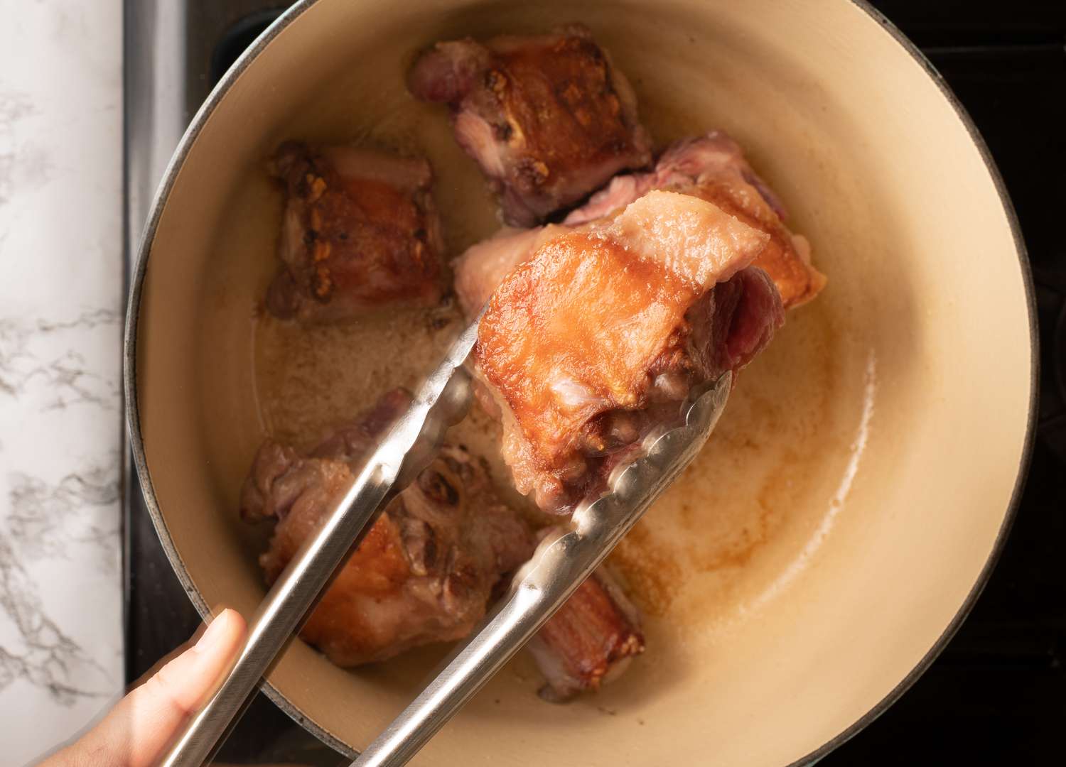 Searing oxtails in a Dutch oven.