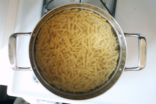 Overhead view of a large pot containing gemelli pasta and water.