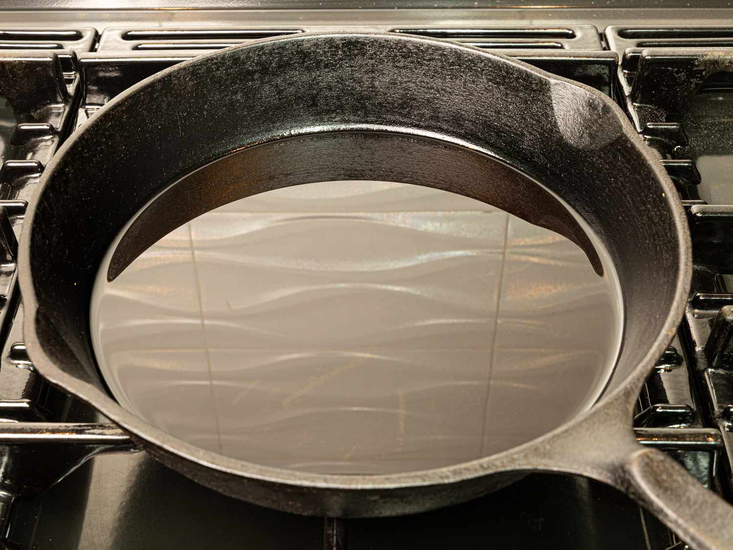 Side angled view of heating oil in a cast iron skillet