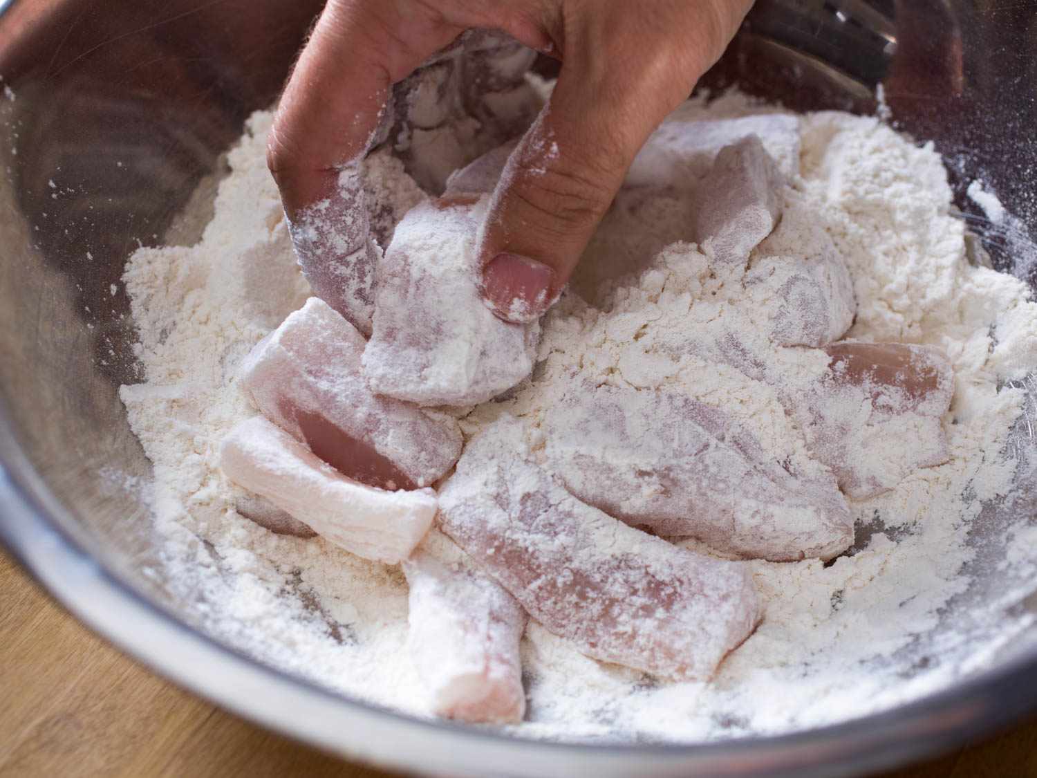 Dredging fish pieces in flour