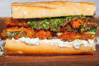 A closeup of a crispy zucchini sandwich with bread ricotta and pesto layers