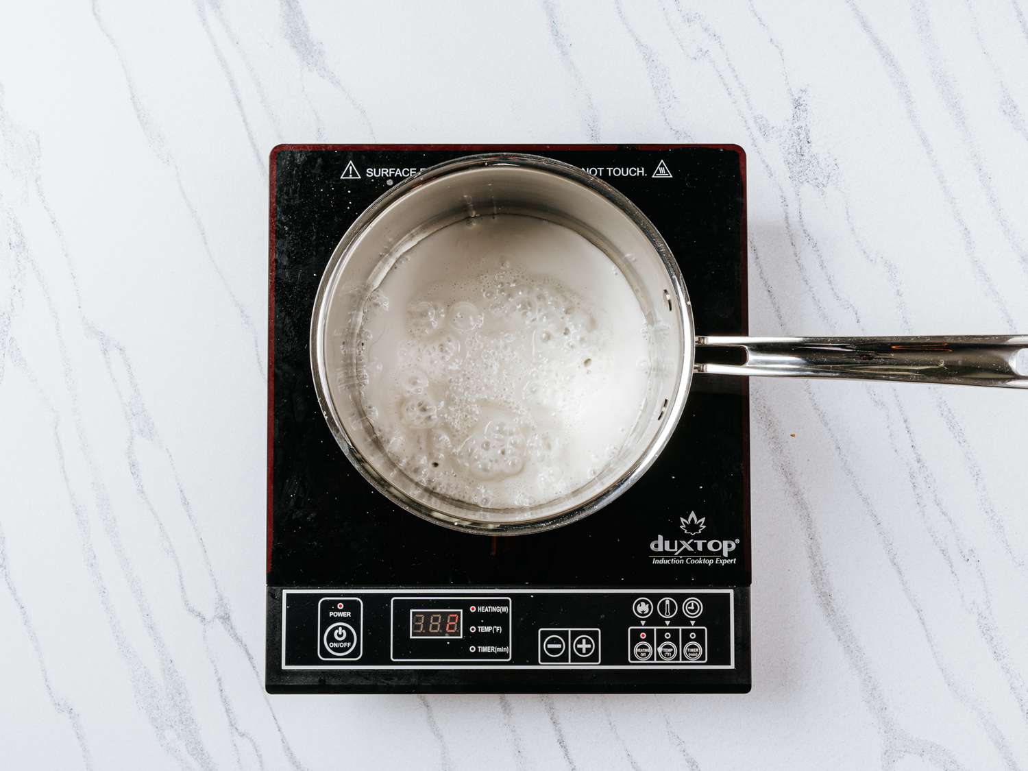 coconut cream cooking in a 2 quart saucepan on a white marble surface 