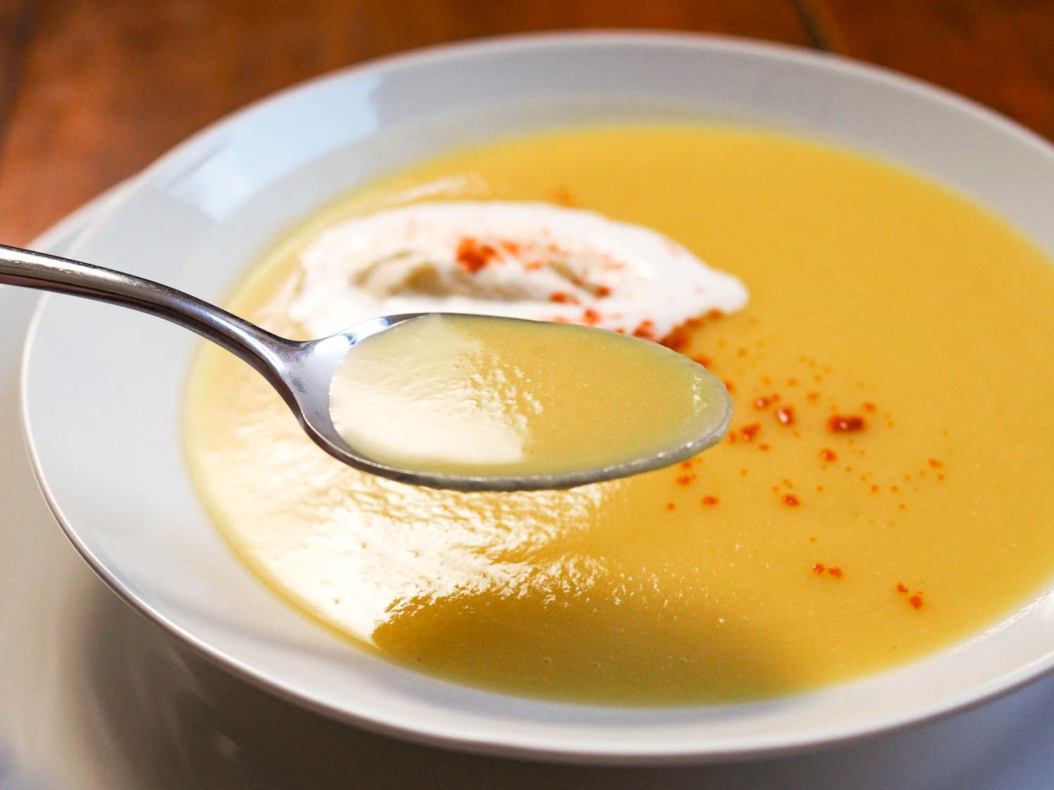 A spoon of creamy spiced parsnip soup is held up for the camera.