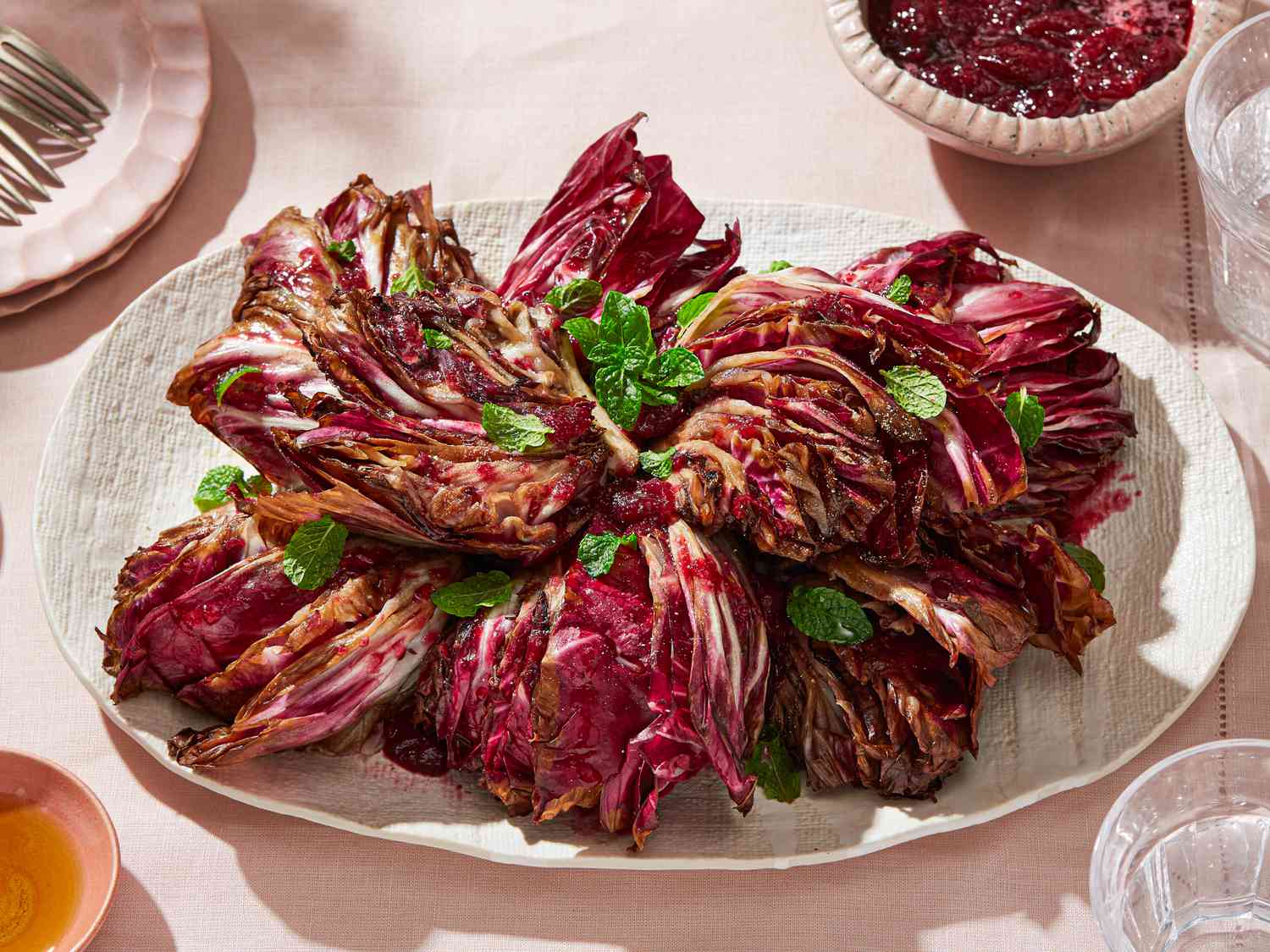 A platter of grilled radicchio garnished with fresh herbs, placed on a set table