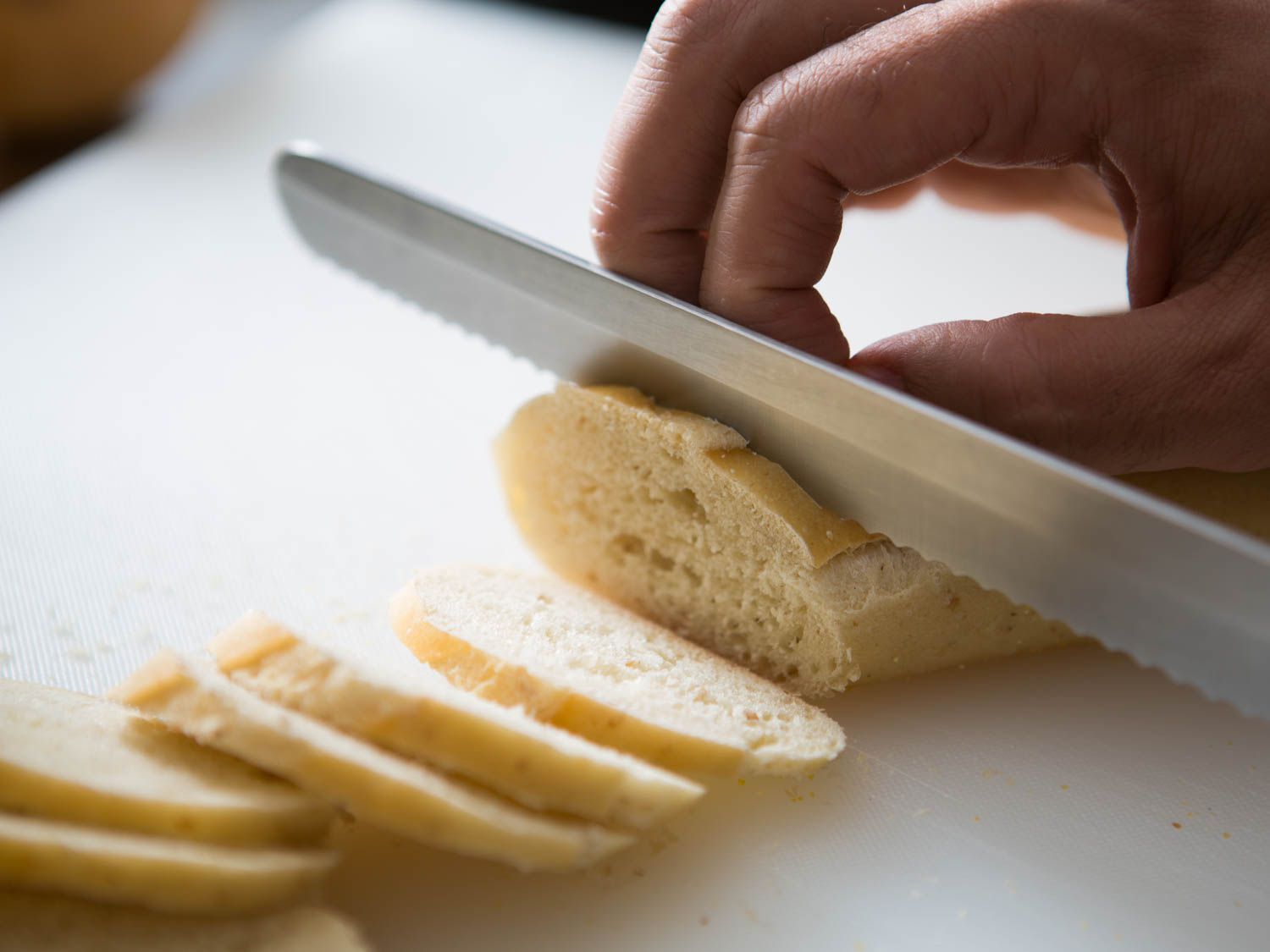 Thinly slicing a baguette to make homemade baguette crackers