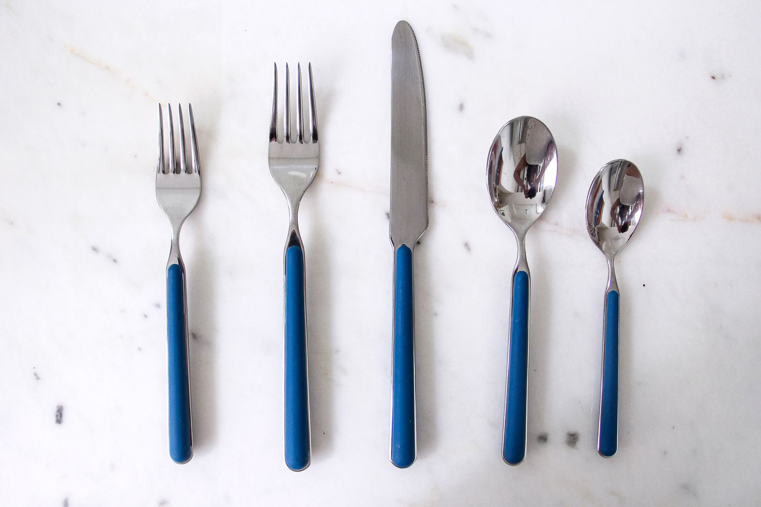 Set of five utensils including forks a knife and spoons on a surface