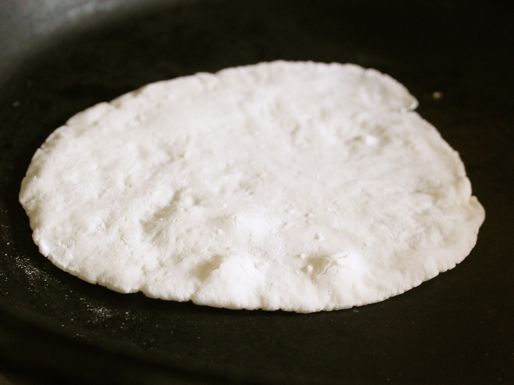 A tortilla round, cooking on a skillet.