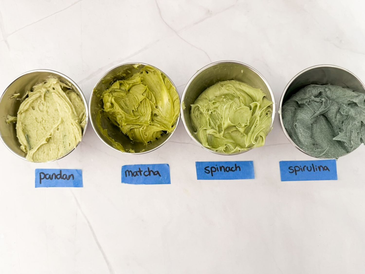 Frosting in small metal containers colored green with pandan, matcha, spinach, and spirulina