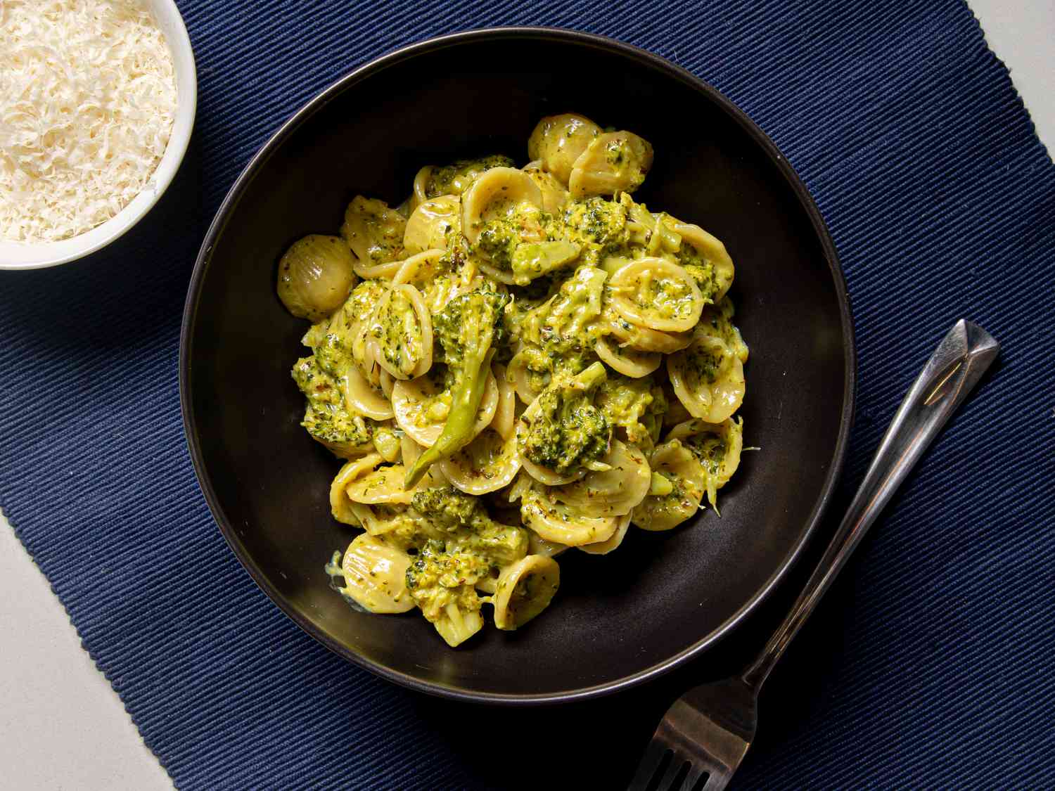 Orecchiette with broccoli and toasted hazelnuts in a black bowl.