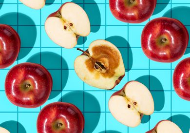 Red apples arranged on a blue grid background some cut in half to reveal their interiors