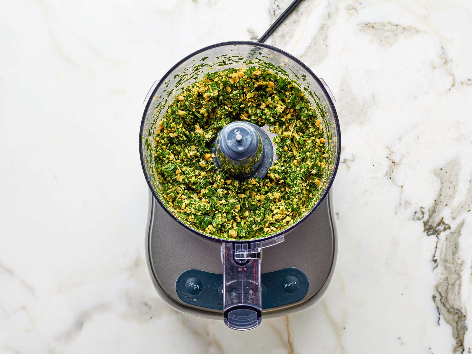 Overhead view of chickpea and parsely mixture formed in a food processor
