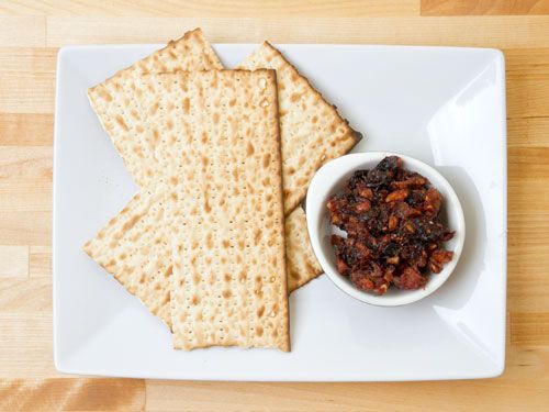 Overhead view of a bowl of Sephardic charoset flanked by several pieces of matzo bread.