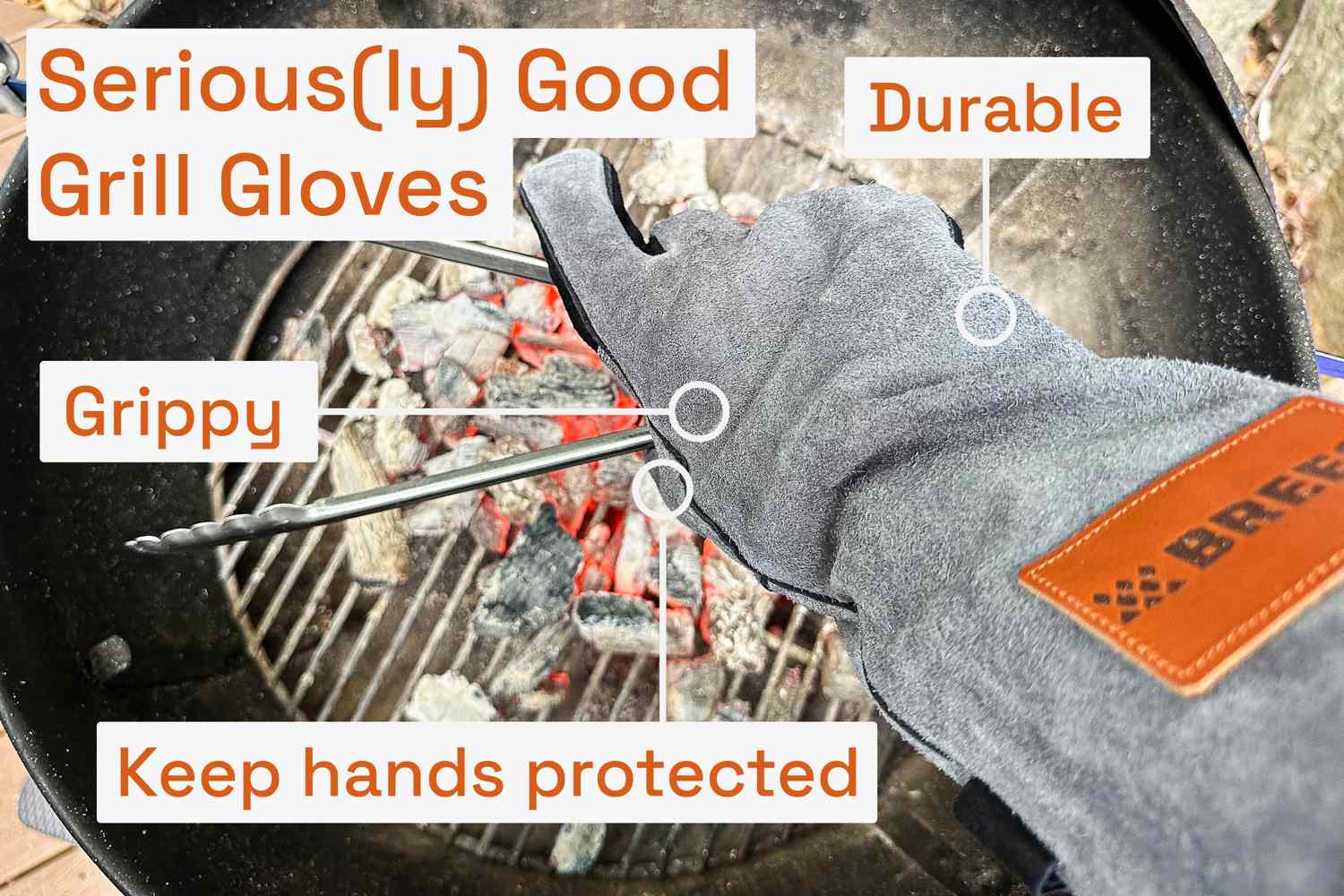 a person using grill gloves to hold tongs over coals in a grill