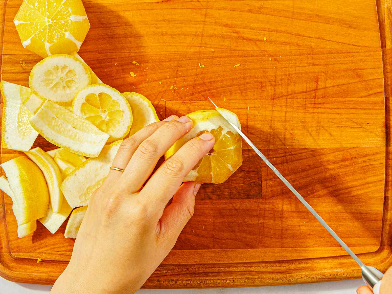 Sliced lemon being peeled and prepared on a cutting board