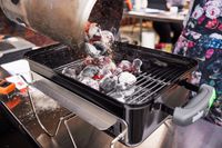 Hot charcoal briquettes poured onto a small grill.
