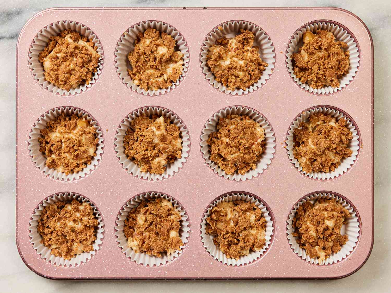 Muffin pan with liners filled with dough and brown sugar mixture 