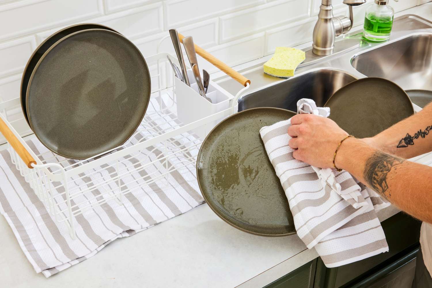 A person using a kitchen towel to dry a plate.