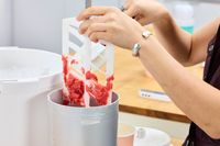 A person using a spatula to remove ice cream from the Hamilton Beach Automatic Ice Cream Maker