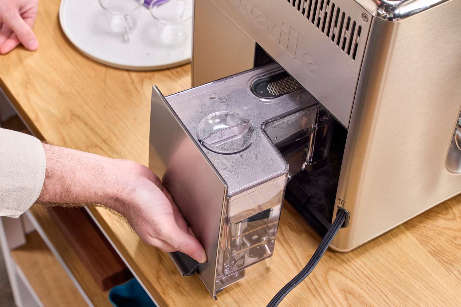 A person removes the water tank from the Breville The Oracle Dual Boiler Espresso Machine