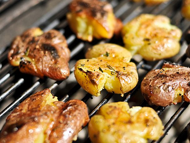 Smashed red and yellow potatoes cooking on the grill.