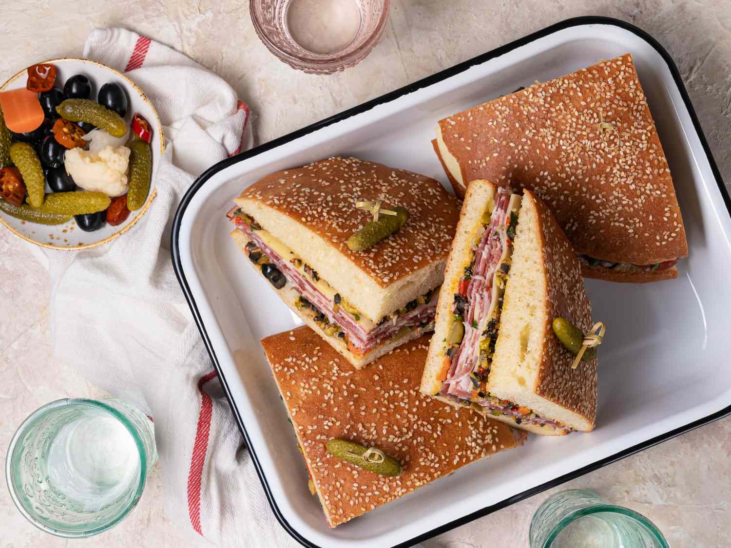 Sliced muffuletta sandwich in an enameled metal tray.