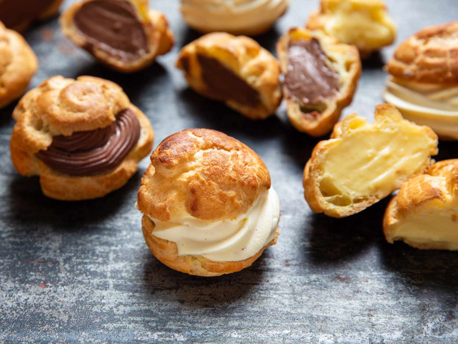 Closeup of cream puffs filled with vanilla, chocolate, and lemon pastry cream.