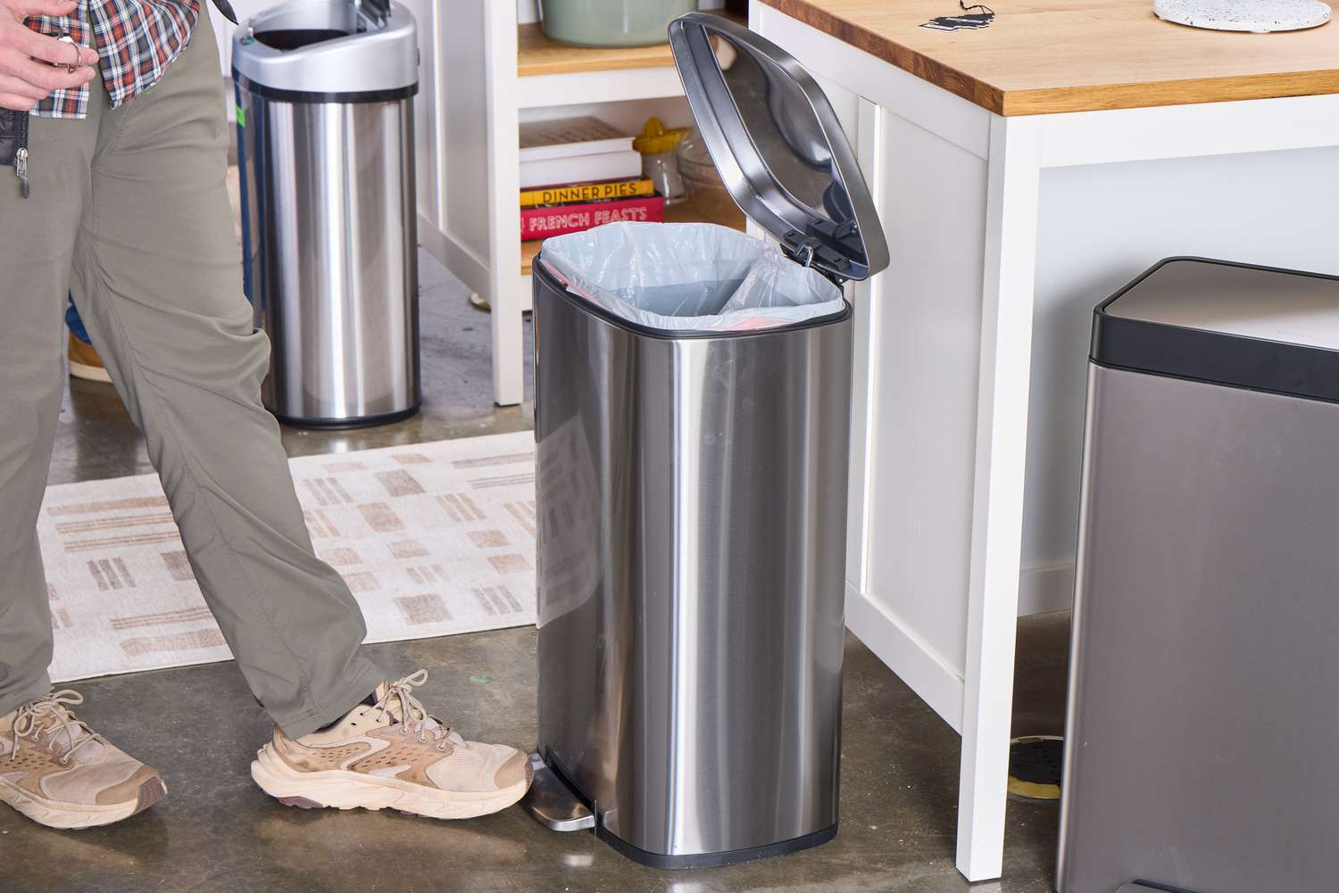 A person presses the foot pedal on the Amazon Basics 13.2 Gallon Soft-Close Trash Can with Foot Pedal