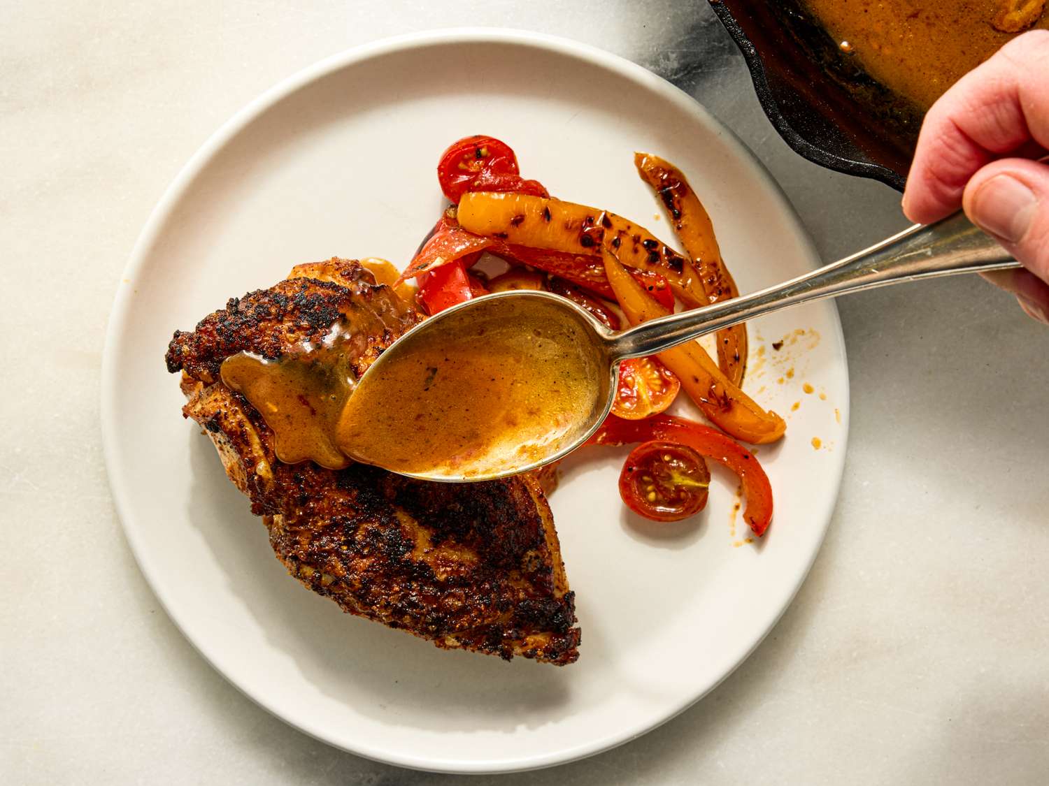 Cooked chicken breast with sauce being served on a plate with vegetables