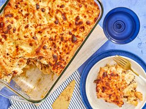 A baked pasta casserole in a glass dish with a portion served on a plate beside it