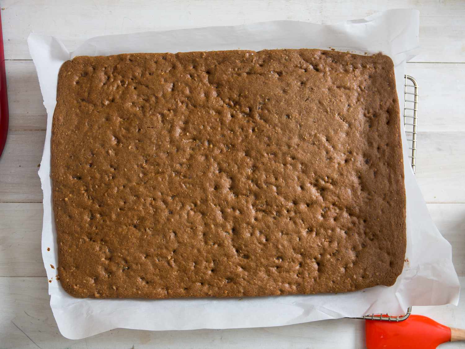 Baked lebkuchen on a sheet of parchment paper placed on a metal rack.