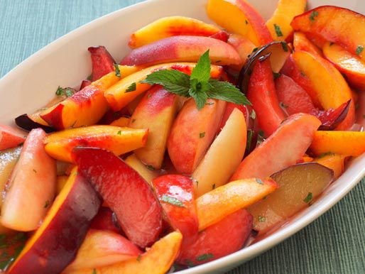 an oval casserole full of sliced peaches, plums and other stone fruit